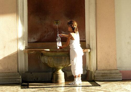 Photo d'un enfant remplissant une bouteille à la source Cachat, à Evian