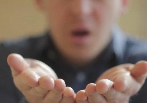 homme soufflant avec les mains tendues