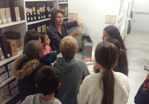 Classe en visite guidée dans les magasins de stockage des documents d'archives.