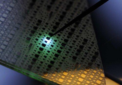L'image montre une plaque fine sur laquelle on distingue des diodes électroluminescentes (de taille millimètrique). L'une d'elle, à laquelle une pointe fine (comme une aiguille) apporte du conrant, émet une lumière bleue