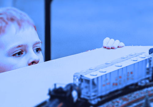 enfant observant attentivement une maquette de  circuit de train
