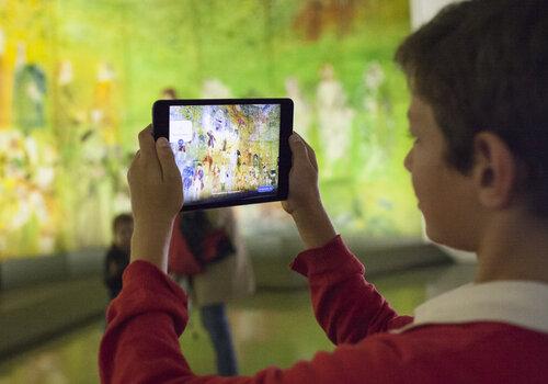 un enfant observe la Fée Electricité par le biais d'une tablette numérique