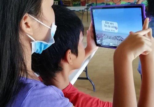 2 jeunes observent la guyane vue du ciel via une tablette Deux jeunes, frère te soeur, tiennent une tablette numérique