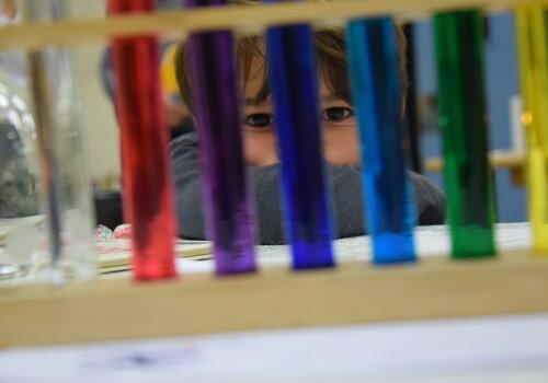 Enfant regardant des tubes à essais contenant des solutions colorées.