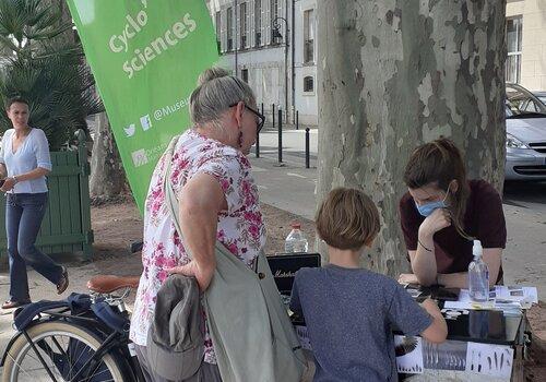 Le Cyclo'sciences du MOBE velo porteur avec une médiatrice et une adulte et un enfant devant