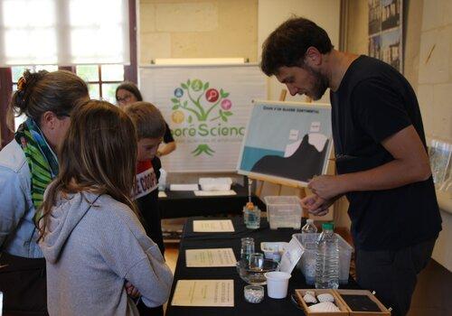 Animateur de l'association Arborescience entourée d'enfants qui participent à l'animation proposée.