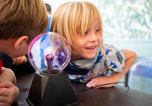 Enfants qui s'interrogent autour d'une boule à plasma