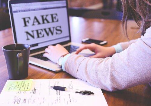 Fausses informations Une personne derrière son ordinateur où il écrit "Fake news"