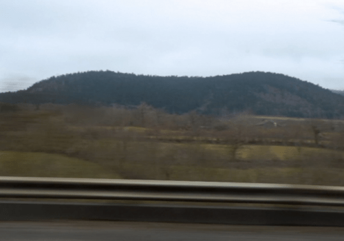 Dialogues itinérants filmés Photo d'un paysage de montagne prise par la fenêtre d'une voiture en train de rouler, créant un effet de flou