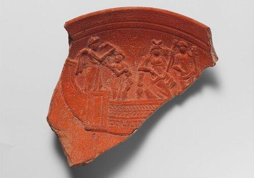 Fragment de bol en terre cuite Isis est assise sur un trône au milieu du navire, flanquée de Déméter tenant une corne d'abondance. À l'arrière du bateau, un Amour ailé chante pour la déesse, et un autre personnage l'accompagne probablement sur un instrument de musique.