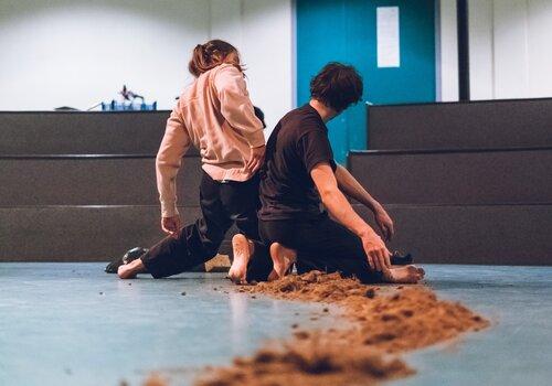 deux danseurs sur scène avec de la terre sur le sol