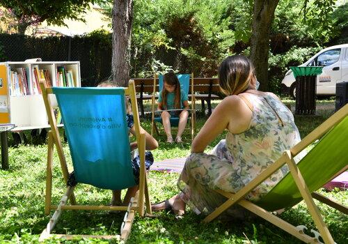 Adulte et enfants lisant sur des transats dans un espace de verdure