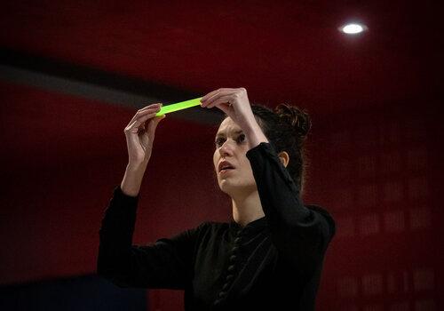 image du spectacle, la comédienne Eugénie Soulard dans le rôle de Marie Curie, observe un échantillon de radium