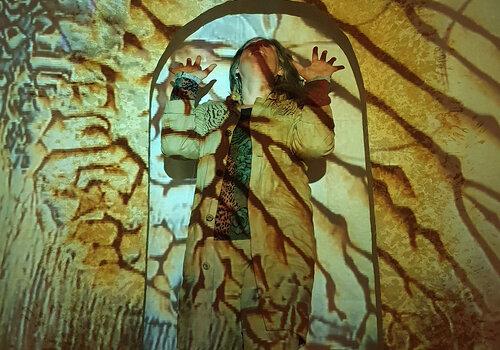 Matière terre agrandie et vue à travers de la lumière, avec une personne en transparence qui s'exclame les mains en l'air. 