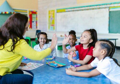 Souvenirs d'école inoubliables Des enfants en classe avec une enseignante. Une enfant 'high five' l'enseignante.