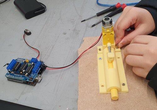 une personnes qui manipule une serrure imprimé en 3d et reliée à une carte arduino