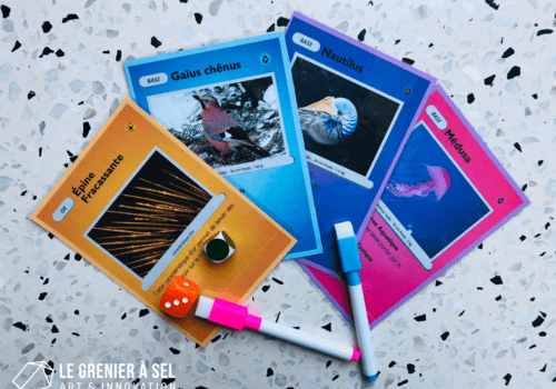 Des cartes de jeu, deux dés, et deux crayons sur une table. 