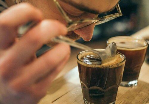 Un homme sent un café avec une cuillère lors d'une dégustation.
