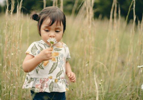 Petite fille sentant une fleur