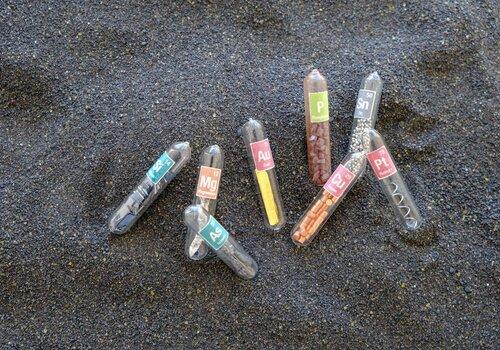 Différents éléments chimiques disposés sur du sable noir 