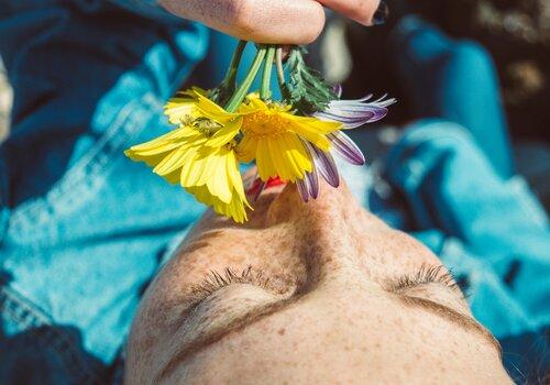 Une personne allongée sent un bouquet de fleurs sauvages