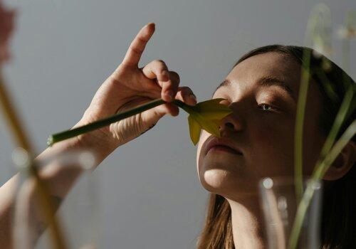 Jeune femme sentant une fleur coupée
