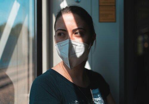 Femme avec un masque près d'une fenêtre