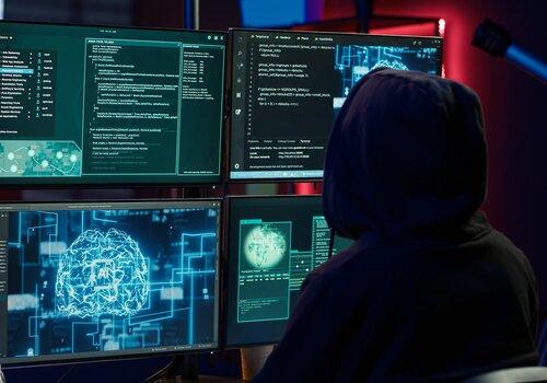 un hacker devant 4 écrans