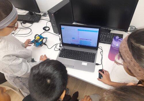 enfants autour d'un portable avec petit robot en train de faire de la programmation