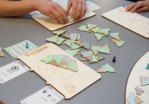 Plateaux, cartes, pions et pièces de jeux vert et marron sur une table avec des mains qui jouent