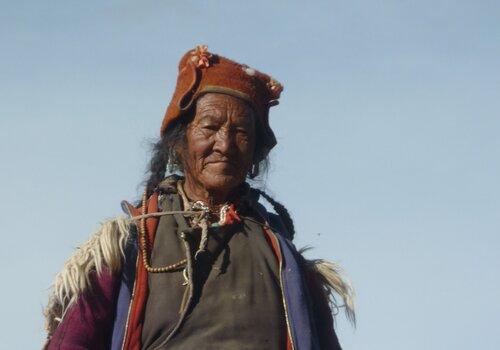 Une femme de l'Himalaya avec couvre-chef orange sur fond de ciel bleu