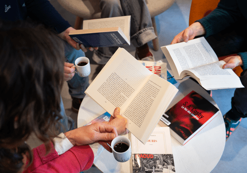 Des personnes tiennent des livres ouverts et des tasses à café