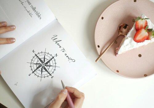 Carnet ouvert main qui écrit et tarte à côté 