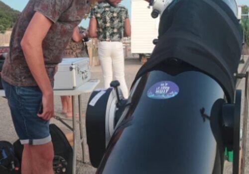un homme regarde à travers l'oeil d'un télescope. il fait jour