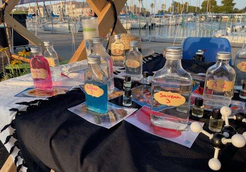 photo d'un atelier avec, posées sur la table, différentes bouteilles arômes, saveurs ainsi que des molécules/atomes.