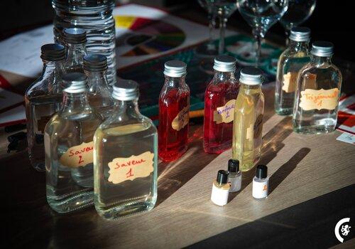 Flacon de liquides multicolore avec des étiquettes de saveurs ou d'arômes.