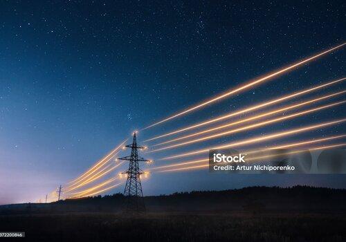  Tours de transmission d’électricité avec des fils orange incandescents contre le ciel nocturne.