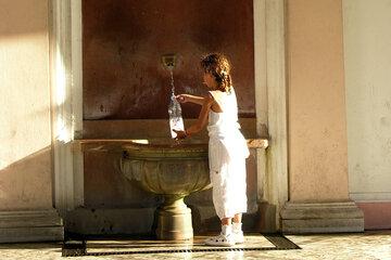 Photo d'un enfant remplissant une bouteille à la source Cachat, à Evian