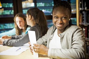 jeune fille souriante avec des papiers dans la main