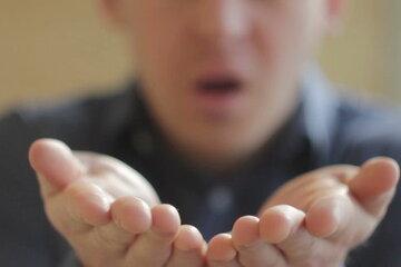 homme soufflant avec les mains tendues