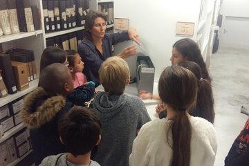 Classe en visite guidée dans les magasins de stockage des documents d'archives.