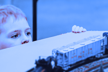 enfant observant attentivement une maquette de  circuit de train