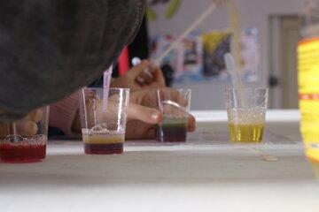 Jeune garçon superposant des liquides de différentes densité à l'aide d'une pipette