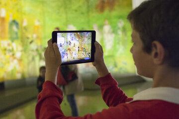 un enfant observe la Fée Electricité par le biais d'une tablette numérique