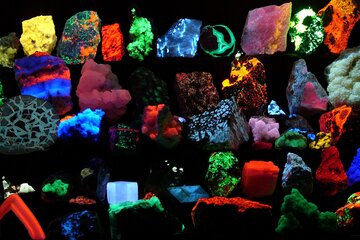 Photographie présentant des minéraux phosphorescents sur un fonds noir.