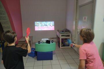 Deux enfants jouent au tennis sur un jeu vidéo