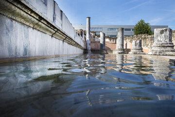 bassin semi-circulaire rempli d'eau ou se reflètent les murs et colonnes romaines