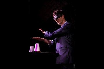 Visuel du spectacle de mentalisme présentant un homme avec les yeux bandés qui fait un tour les mains au-dessus de gobelets.