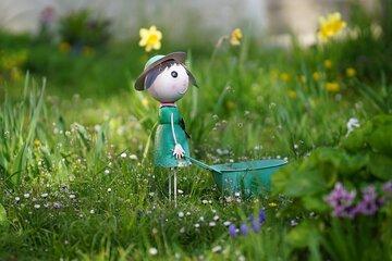 Les sept justifications de l'écologie : un petit personnage miniature tient une mini brouette dans un beau jardin 