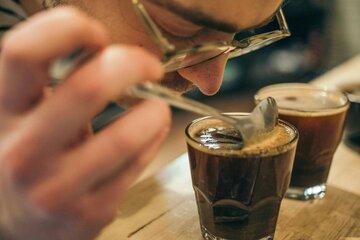Un homme sent un café avec une cuillère lors d'une dégustation.